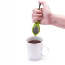 Load image into Gallery viewer, A hand holding a green tea infuser strainer over a white ceramic mug filled with tea, shown against a plain white background.